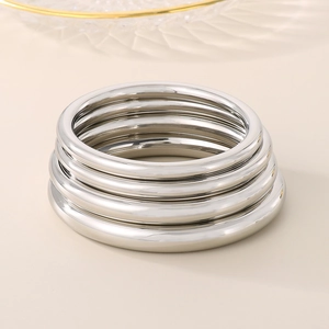 Polished silver stainless steel hollow bangles stacked in a minimalist arrangement