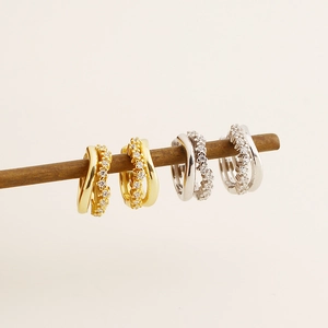 Macro shot of silver and gold S925 huggie earrings with sparkling inlaid rows of stones