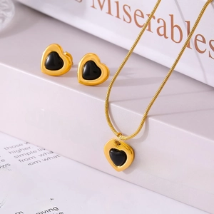 Retro gold heart necklace and stud earring set with black stone on vintage book backdrop