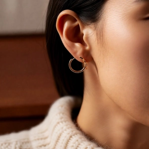 Close-up of a 18k gold plated hoop earring with a stylish lock mechanism on woman ear