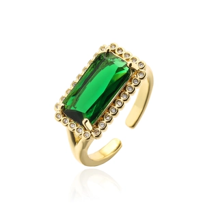 Detail of emerald cut green zircon ring with gold plating and paved stones