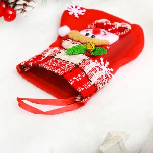 Close-up of red felt Christmas stocking with snowman doll, bell and festive decorations