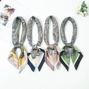 Flat lay of silk scarves with paisley patterns in mustard, navy, pink, and green colors