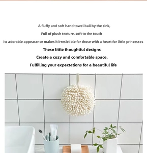Close-up of soft cream chenille hand drying ball with hanging loop on white tile wall