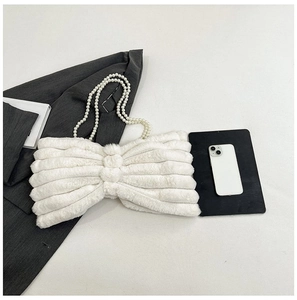 Detailed close-up of a white plush bow-shaped handbag with elegant faux pearl strap