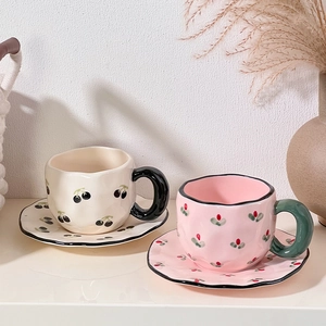 Detailed view of cream and pink ceramic coffee cups with wavy edges on a shelf