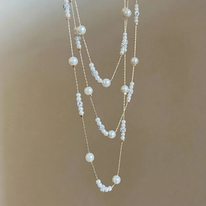 Detailed macro view of layered gold chain necklace with white pearls and crystal balls