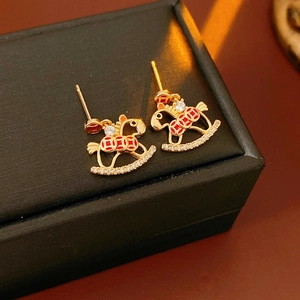 Golden rocking horse earrings with red enamel and zircons on a black gift box