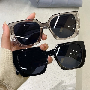 Detail of trendy geometric cat eye sunglasses in translucent grey and glossy black frames