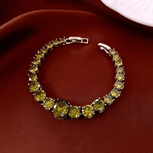 Detailed close-up of olive green zircon bracelet with silver metal on red silk background