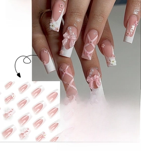 Detail of pink French press-on nails with 3D bows, white flowers, and pearl accents