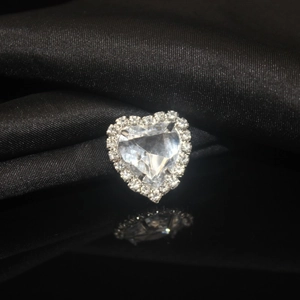 Macro detail of heart crystal sewing gem with silver claw setting on black silk