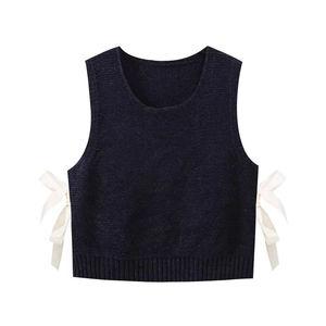 Detail view of navy knit vest featuring white side-tie bow accents and fine texture