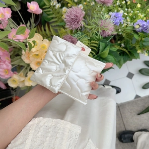 Close-up of heart-quilted satin storage bag with snap button and brand tag in garden