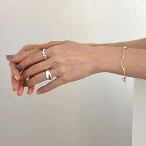 Close-up of minimalist S925 sterling silver rings and delicate bead chain bracelet