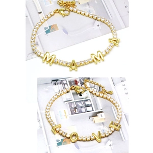 Detail of gold LOVE and MAMA bracelets featuring zircon pavé settings and adjustable chains