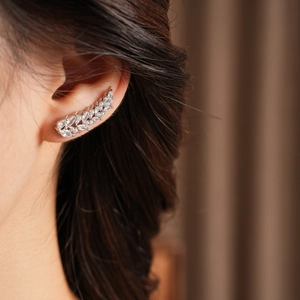 Close-up of a silver feather ear cuff featuring sparkling zircons worn by a model