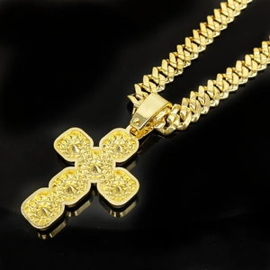 Macro detail of golden cross pendant featuring fine textures on a classic Cuban link chain