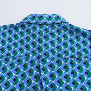 Détail du col de chemise montrant des motifs géométriques bleus et verts élégants