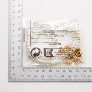 Detail view of gold starfish and shell pearl anklet measurement next to a metal ruler