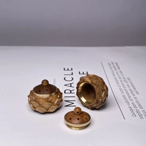 Detail of pinecone-shaped sandalwood sachet with brass screw cap and carved wood texture