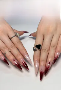 Detail of stiletto press-on nails with red fire gradients and white dragon patterns