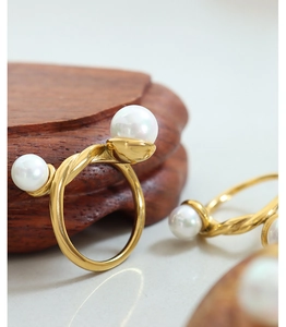 Detailed macro view of a gold braided open ring featuring two elegant white pearls