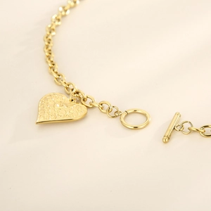 Close-up of golden stainless steel heart pendant with T-bar toggle clasp on a bracelet