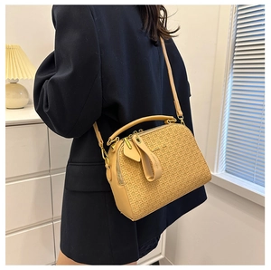 Detail of khaki woven texture and smooth leather handle on a chic crossbody bag