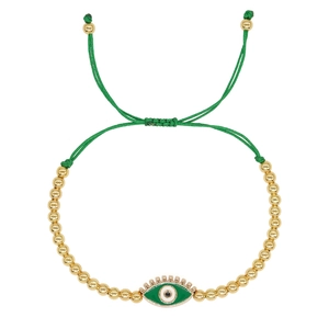 Detail of green evil eye charm on adjustable gold beaded bracelet with green woven cord