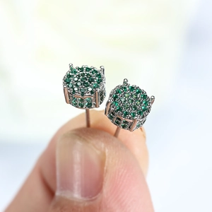 Macro shot of silver four-claw stud earrings featuring green pavé-set round cubic zirconia