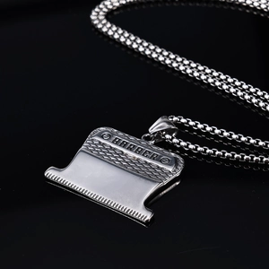 Macro shot of silver stainless steel barber blade pendant with Barber text engraving