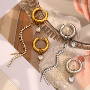 Detail of asymmetrical 18K gold plated earrings with zircon heart and tassel charms