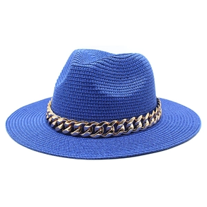 Detail of wide-brim dark blue straw fedora hat with chunky gold chain decoration