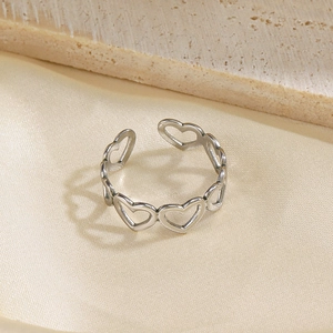 Bague ouverte en argent avec cœurs évidés sur un fond de soie élégant