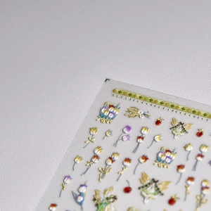 Macro shot of 3D embossed nail art stickers featuring fairies, tulips and cherry motifs