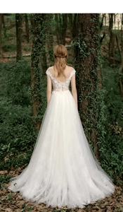 Lace wedding dress with open back and tulle skirt shown in a lush forest setting
