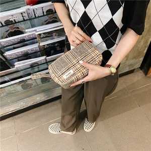 Gros plan détaillé d'une trousse de maquillage à carreaux élégante tenue par un mannequin