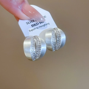 Detail of brushed silver C-shaped stud earrings with micro-set zircons on white card