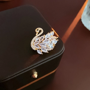 Macro shot of a gold-plated swan brooch with sparkling cubic zirconia on a leather case