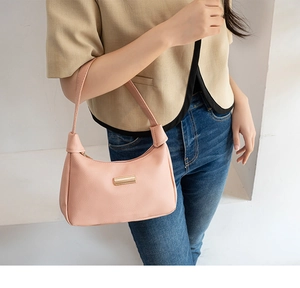 Detail of pink pebbled leather underarm bag featuring a modern gold metal buckle strap