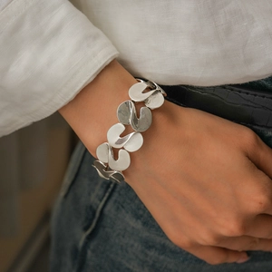 Close-up of abstract irregular silver metal link bracelet worn on woman's wrist