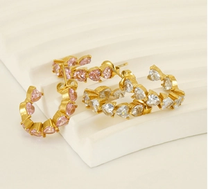 Detail of C-shaped gold earrings with heart-cut pink and clear cubic zirconia stones