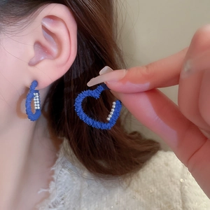 Detailed view of dark blue velvet heart earrings with tiny pearl accents on woman