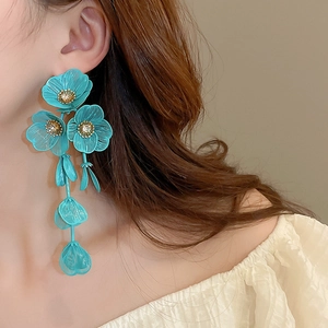 Detailed view of long turquoise flower petal tassel earrings on a model's ear