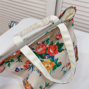 Close-up of floral cotton tote bag showing silver zipper closure and woven handle