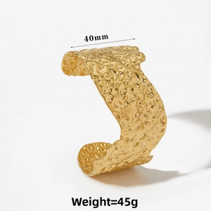 Detail of 40mm wide gold cuff bracelet featuring an irregular hammered texture surface
