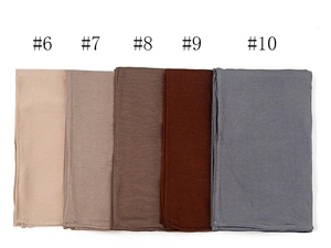 Detailed stack of soft mercerized cotton scarves in beige, brown, and grey neutral tones