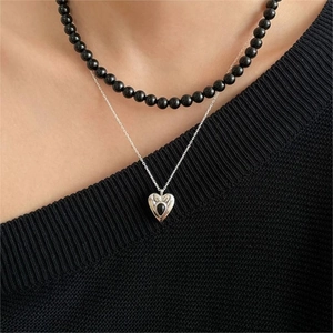 Close-up of double-layer necklace with black beaded chain and silver heart pendant