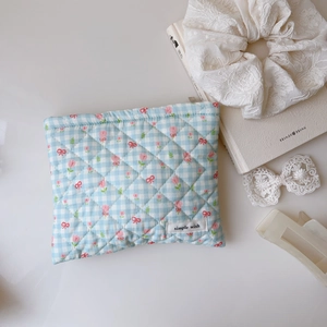 Pochette matelassée à carreaux avec imprimé tulipes et nœud sur un bureau